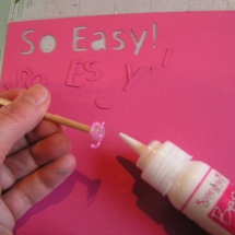 The fine tip of the Best Glue Ever applies glue while Embellie Gellie holds the small die cut letter.